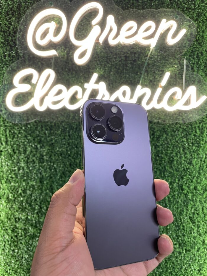 iPhone 14 Pro color morado oscuro en mano frente a letrero Green Electronics barato
