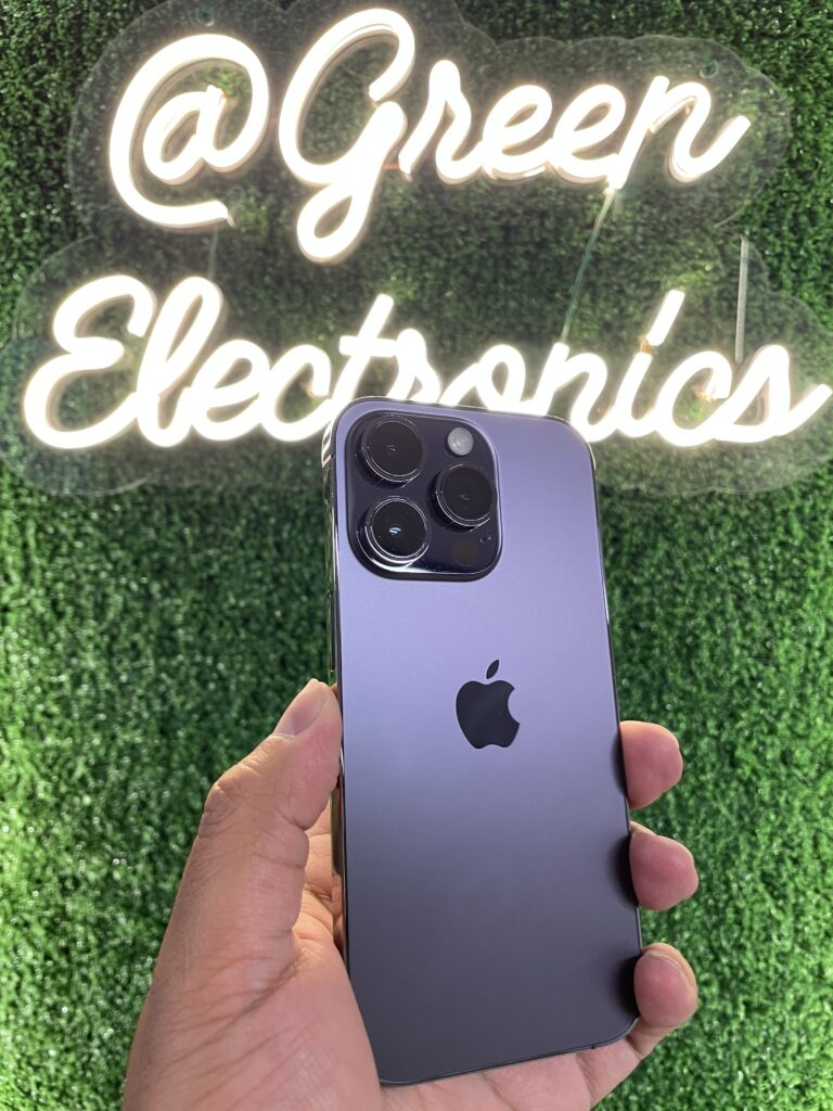 iPhone 14 Pro color morado oscuro en mano frente a letrero Green Electronics barato