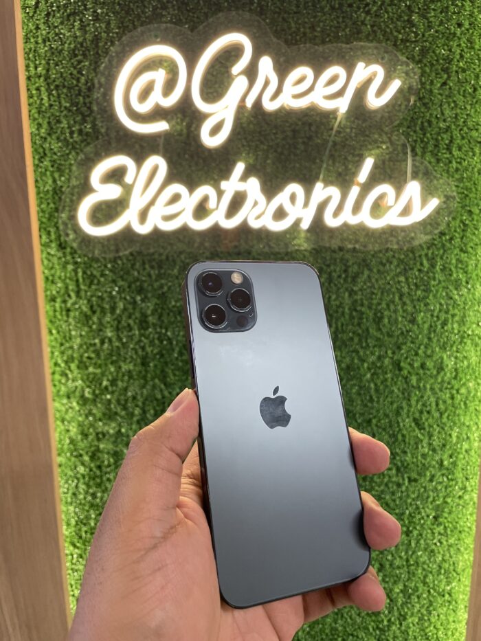 iPhone 12 Pro color grafito en mano frente a letrero Green Electronics