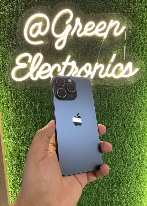 Celular usado en Colombia de alta calidad iPhone 15 Pro Max azul en mano frente a letrero Green Electronics