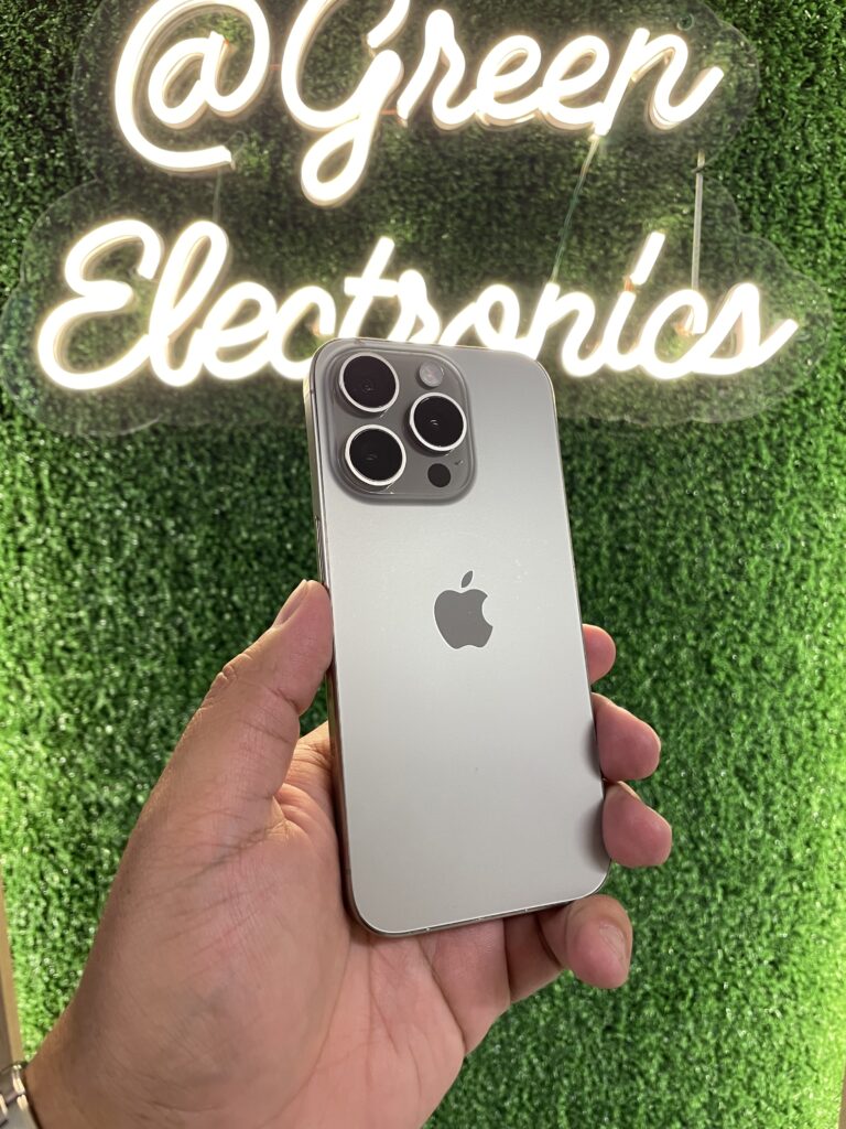 iPhone 15 Pro color titanio natural en mano frente a letrero Green Electronics